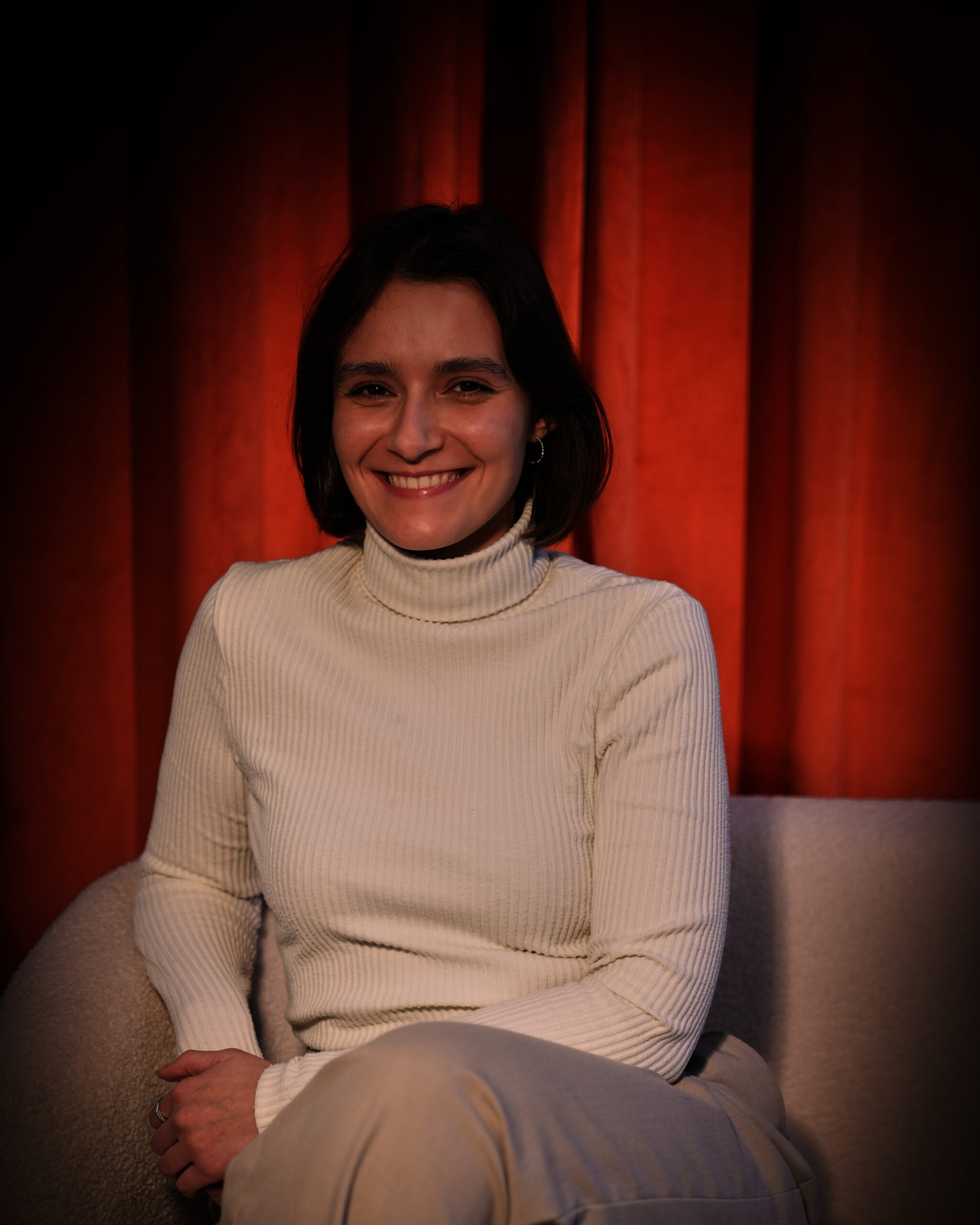 Eine Person sitzt auf einer Couch und lächelt in die Kamera